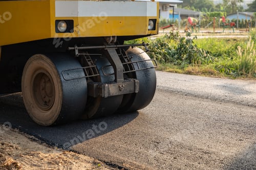 Preview: Yellow steamroller or soil compactor working on asphalt road at construction site