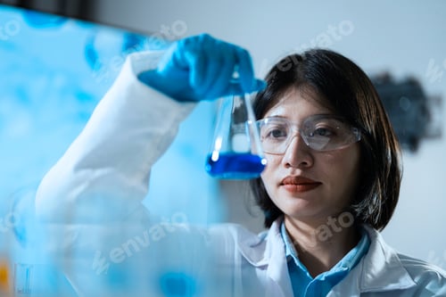 Preview: A woman in a lab coat holding a beaker with a blue liquid in it