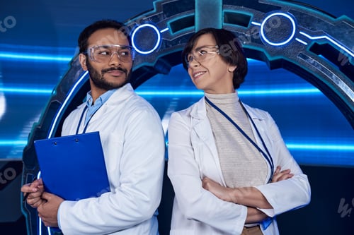 Preview: innovative lab, multiethnic scientists smiling at each other near neon-lit experimental device