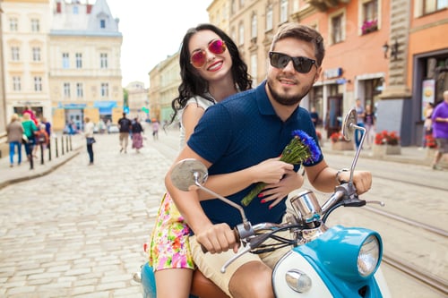 Preview: young beautiful hipster couple riding on motorbike city street