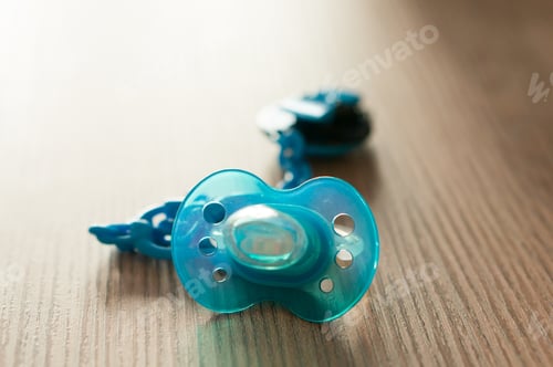 Preview: Closeup shot of a blue pacifier on a table with a blurred background