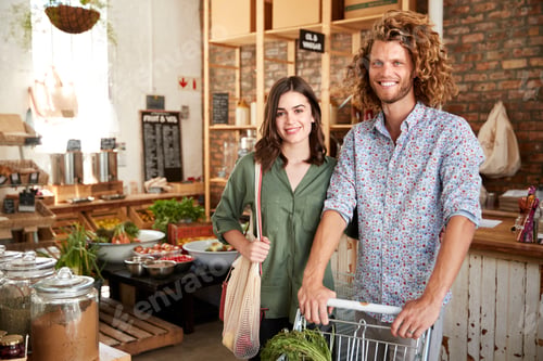 Preview: Portrait Of Couple With Trolley Buying Fresh Fruit And Vegetables In Plastic Free Grocery Store