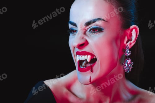 Preview: vampire showing her fangs and looking away isolated on black