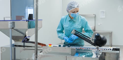 Preview: Pharmacy industry woman worker in protective clothing operating production of tablets in sterile