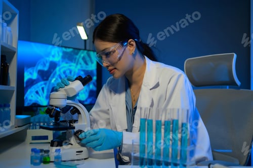 Preview: A woman in a lab coat is looking at a microscope