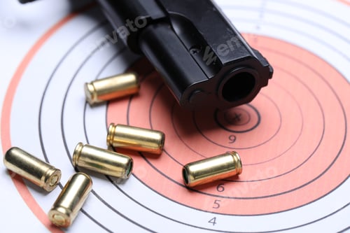 Preview: Many metal cartridges and gun on shooting target, closeup