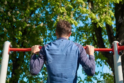 Preview: Man doing pull-ups on outdoor horizontal bar