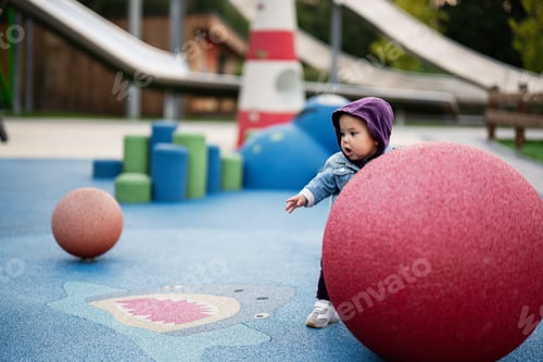Preview: Curious toddler explores colorful playground with large red ball