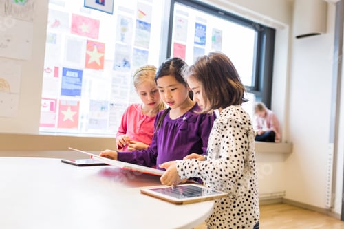 Preview: Three young students engaged in reading together at school.
