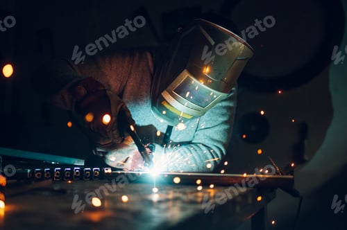Preview: Man worker welding metal with welding machine in a factory or workshop