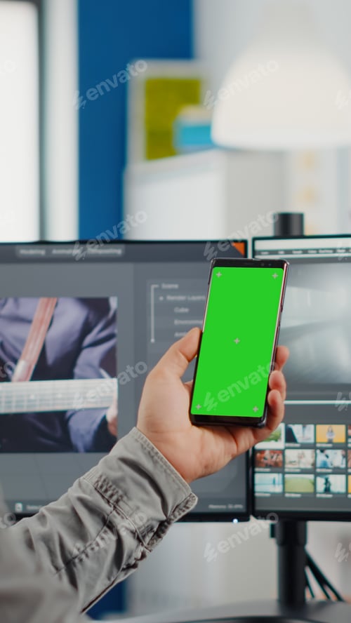 Preview: Video editor talking on video call holding smartphone with green screen