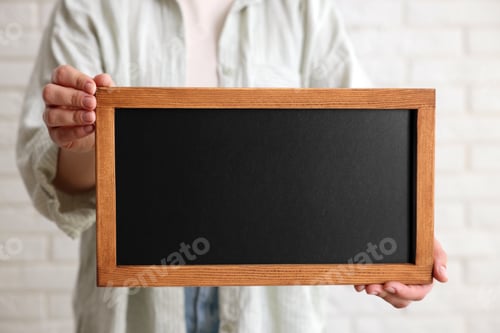 Preview: Woman holding blank small blackboard indoors, closeup
