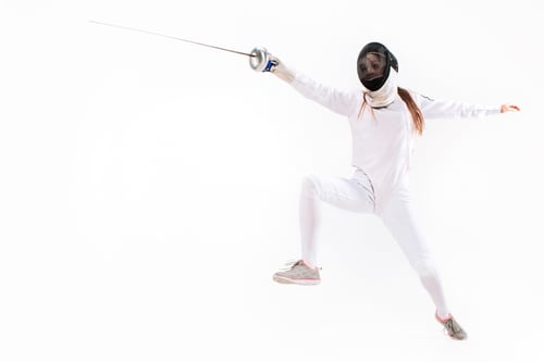 Preview: Man wearing fencing suit practicing with sword against gray