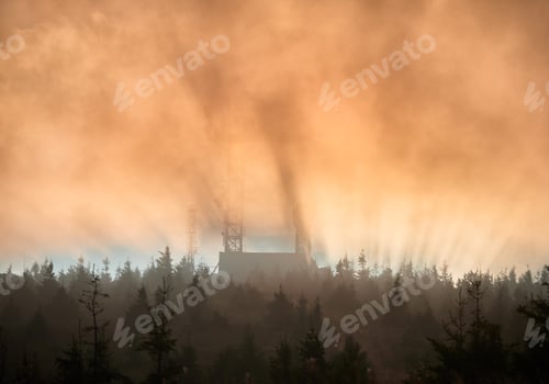 Preview: Sun rises, its rays pierce through the mist, casting dramatic beams of light over landscape.