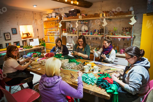 Preview: Group of people, women around a table in workshop, making paper flower wreaths.