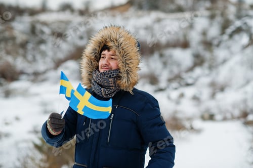 Preview: Scandinavian man with Sweden flag in winter swedish landscape.