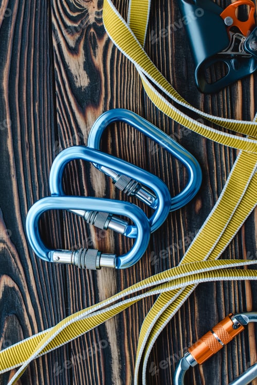 Preview: Isolated photo of climbing equipment. Parts of carabiners lying on the wooden table