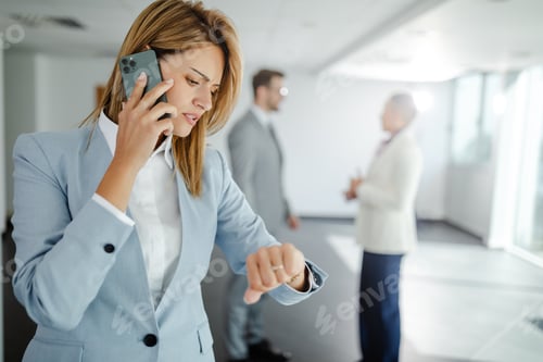 Preview: Close up photo of young businesswoman having phone call while standing in hallway before meeting.