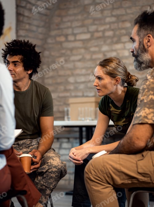 Preview: Female soldier talking with diverse group of veterans during PTSD support group.