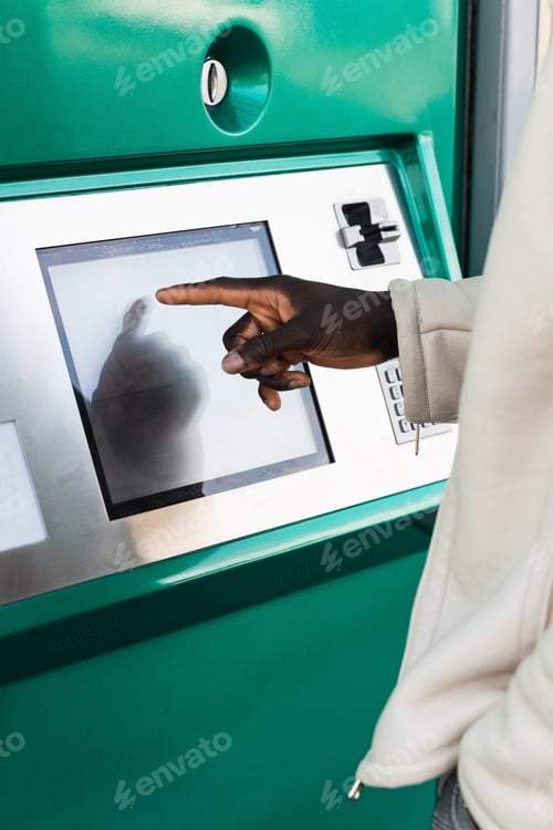 Preview: Anonymous black businessman touching screen of ATM in town