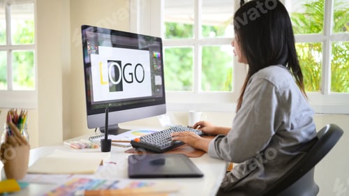 Preview: Graphic designer working on computer creating logo design, using design software