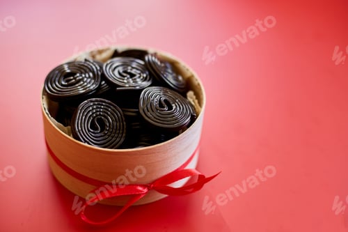Preview: Tasty black liquorice candies in present box on red background