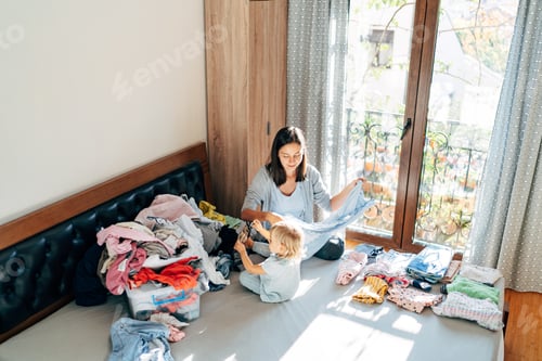 Preview: Mom and daughter are folding clothes home.