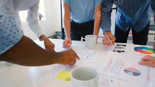 Preview: Close Up Of Multi-Cultural Business Team Standing Around Table Discussing Documents In Office