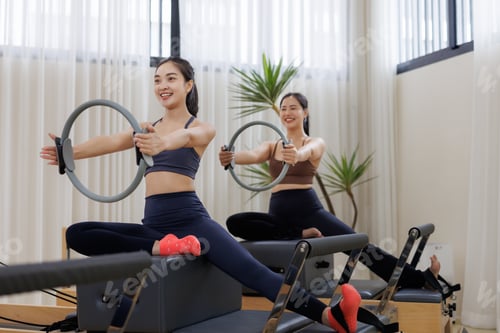 Preview: Women training with pilates ring on reformers
