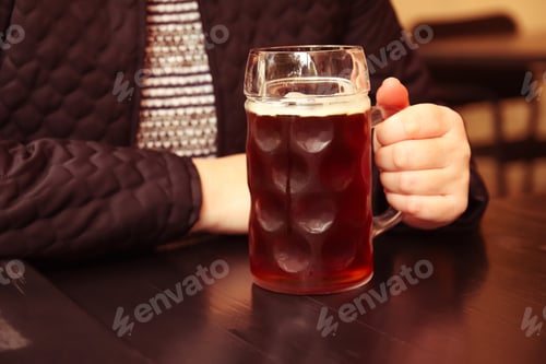 Preview: Dark beer. mug of dark beer. Closeup of two hands clinking beer stein glasses. People, woman or man