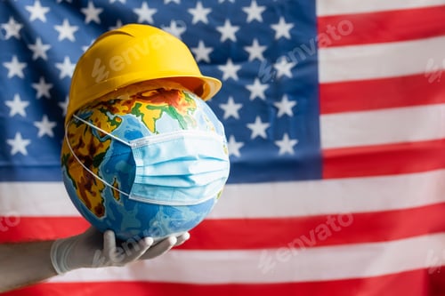 Preview: cropped view of man in latex glove holding globe with hardhat and medical mask near blurred usa