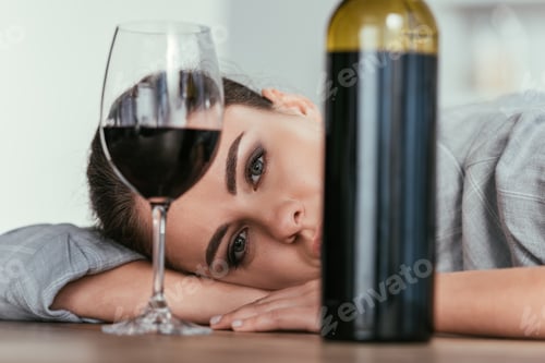 Preview: Selective focus of woman looking at camera with wine glass and bottle on table