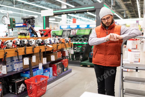 Preview: man stores power tools confused looks at his watch