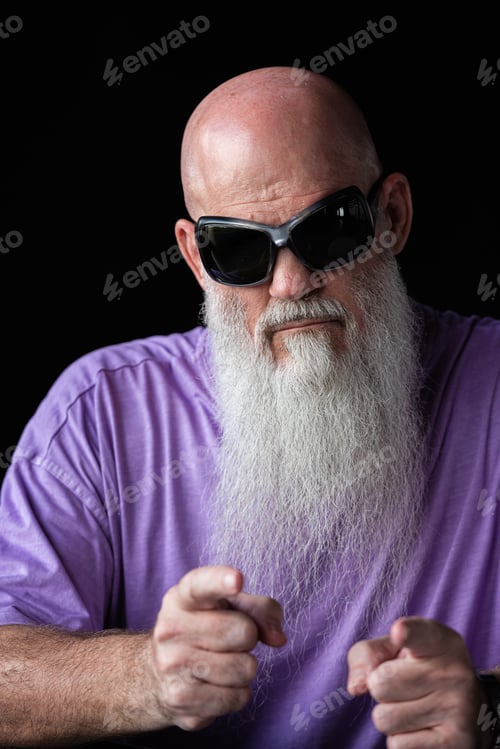 Preview: Portrait of man with long gray beard wearing purple t-shirt and sunglasses pointing finger at camera