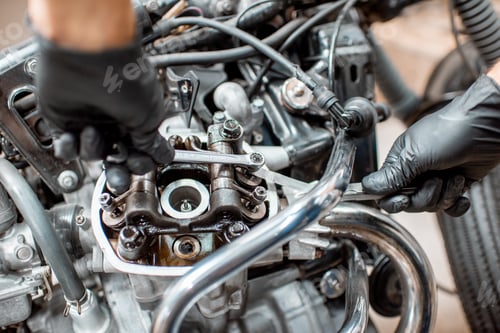 Preview: Worker repairing motorcycle engine at the workshop