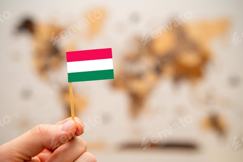 Preview: Hungary flag in mans hand on the world map background.