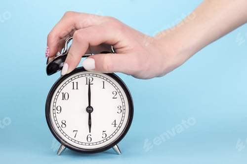 Preview: Close-up woman's hand clamps the alarm clock closeup