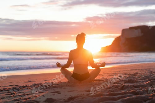 Preview: Woman on the beach at sunset meditating