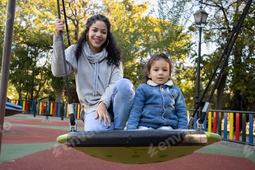 Preview: Portrait of hispanic mother and son on a spider swing enjoying time together and looking at camera