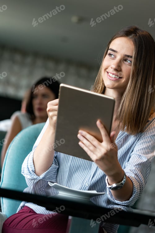 Preview: Happy woman manager holding tablet and sitting in cafe
