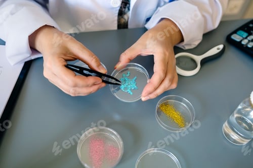 Preview: Unrecognizable female chemist technician examining blue glitter in facial cream sample on laboratory