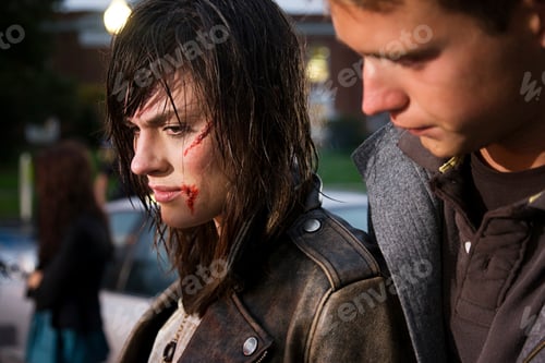 Preview: A moment of concern as a young man looks over at a distressed woman with a bloodied face