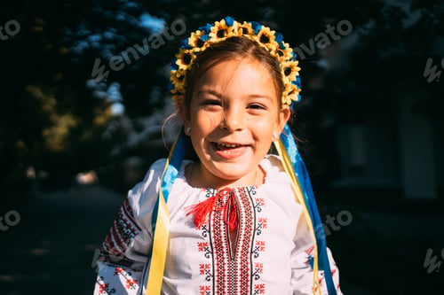 Preview: Child girl in Ukrainian traditional clothes and flower wreath is praying outdoors in a sunlight