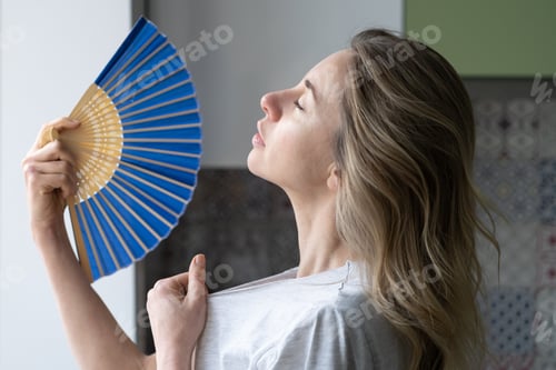 Preview: Overheated woman in t-shirt using wave fan suffer from heat sweating, cools herself, feels sluggish