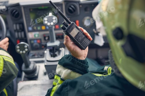 Preview: Firefighter holding walkie talkie at fire machine