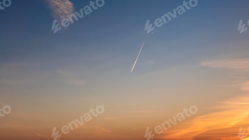 Preview: Passenger plane flying in the blue sky at sunset, fast transport vapor trails