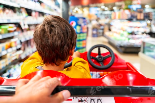 Preview: Child driving shopping cart in supermarket with parent pushing