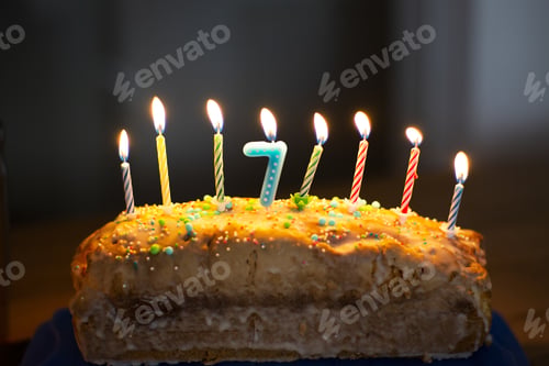 Preview: Closeup shot of a birthday cake with burning candles for a 7 years-old