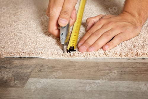 Preview: Man cutting new carpet flooring indoors, closeup. Space for text