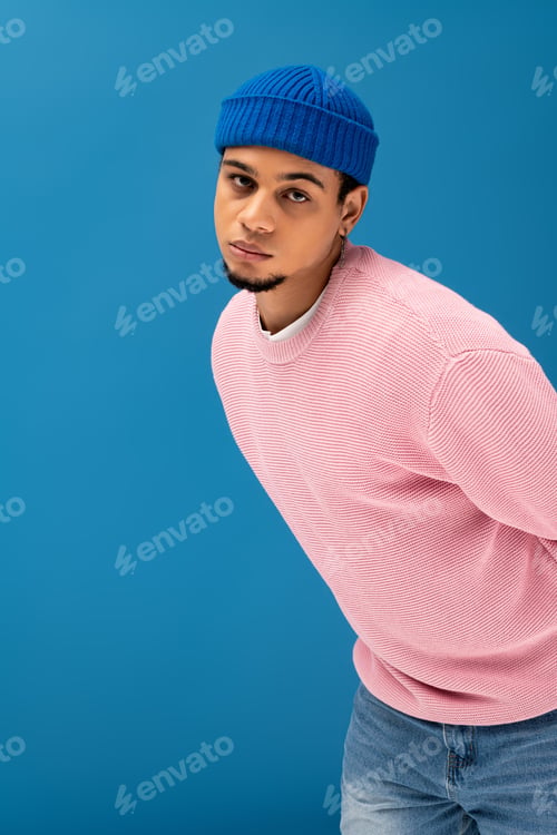 Preview: Stylish young man showcases modern fashion against a vivid blue backdrop